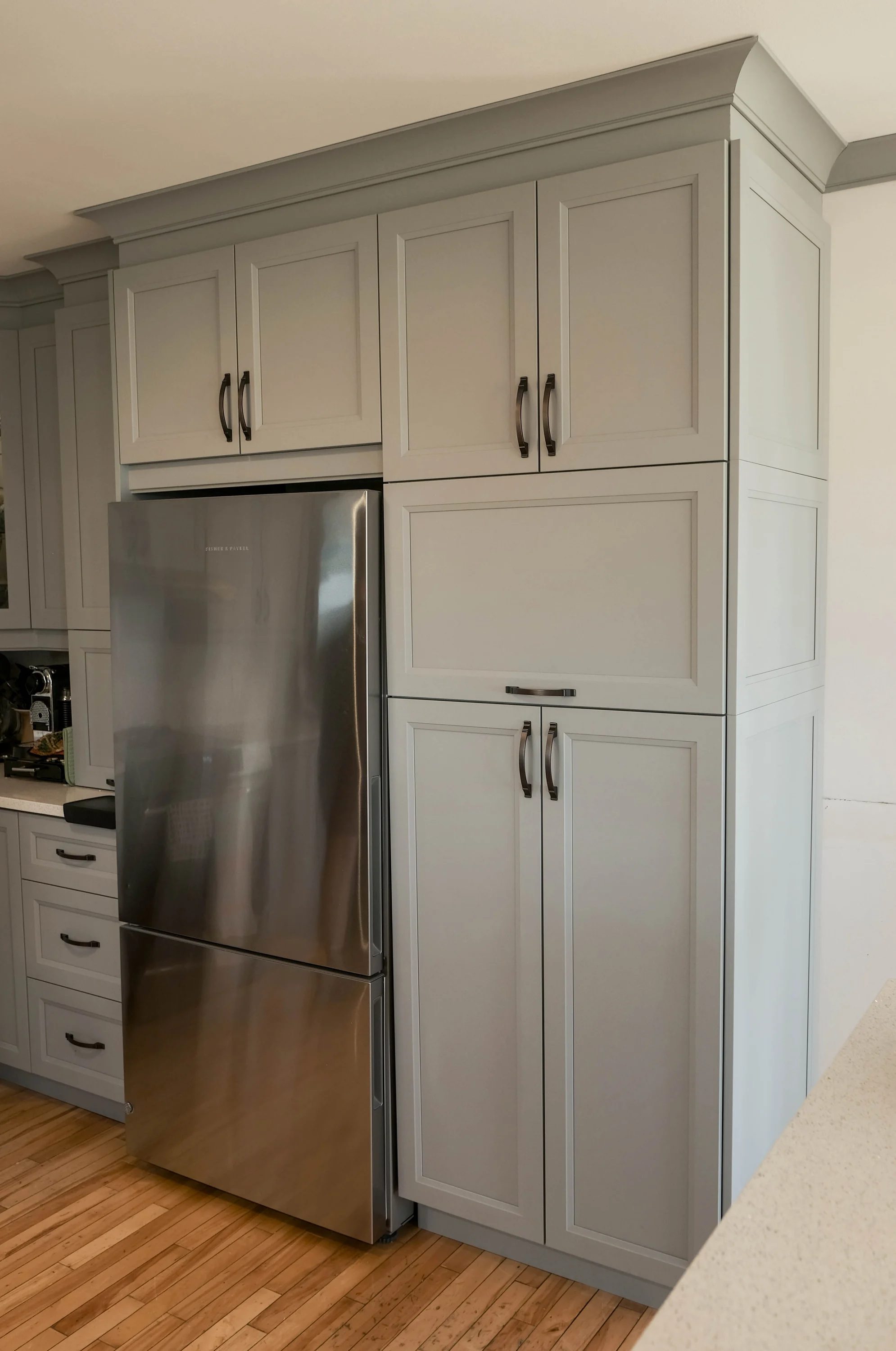 Garde-manger sur mesure à portes Shaker grises encadrant le réfrigérateur, Atelier Multidécor