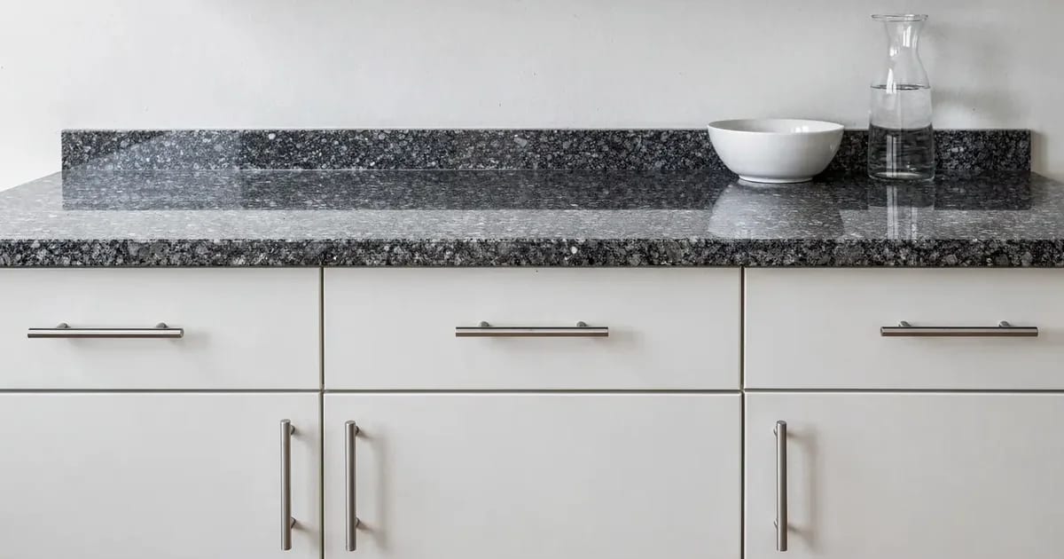 Reference illustration: polished dark grey granite countertop with visible crystals, on white melamine cabinets.